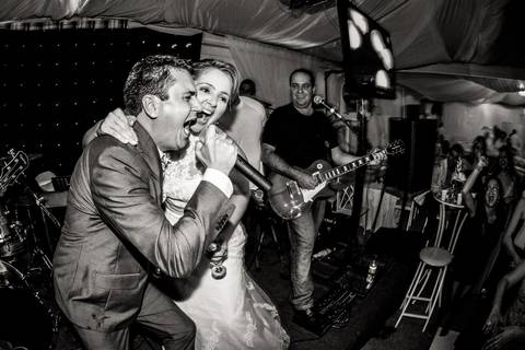 Noivo e noiva cantam durante a Recepção acompanhados de banda em foto preta e branca'