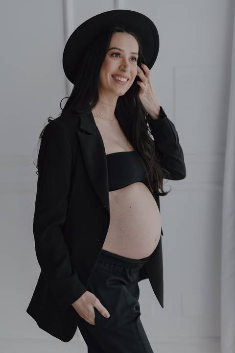 Gestante linda com look social para ensaio em estúdio de luz natural'