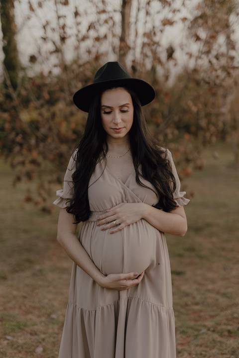 Gestante linda com chapéu em ensaio no por do sol '