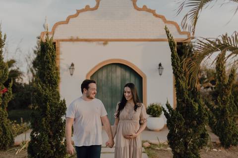 Casal caminhando em ensaio de gestante na chácara com capela'