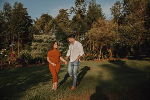 Casal caminhando no campo em ensaio de gestante '
