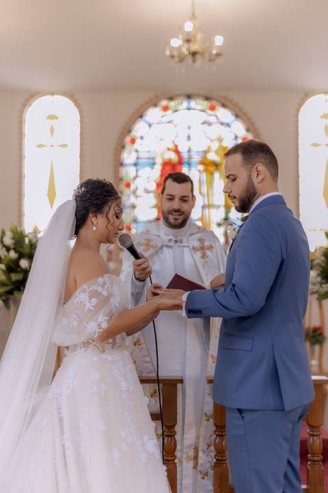 noiva colocando aliança na mão de seu noivo'