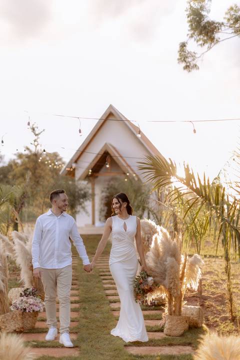 Casal caminhando em frente a capela do casamento'