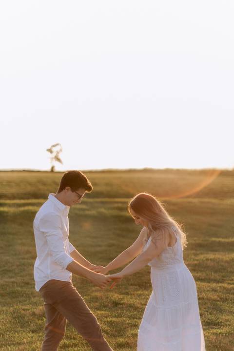 foto espontânea de casal no campo com por do sol'