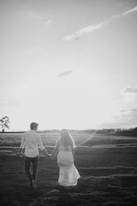 casal caminhando no campo com por do sol'