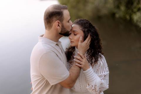 Noivo beijando a testa de sua linda noiva abraçado junto a ela'