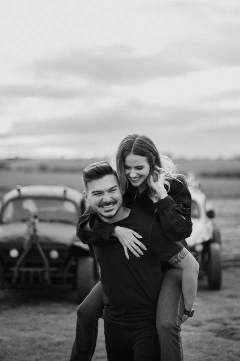 Foto criativa para casal em ensaio pré wedding com carro personalizado fusca antigo com rodas para trilha'