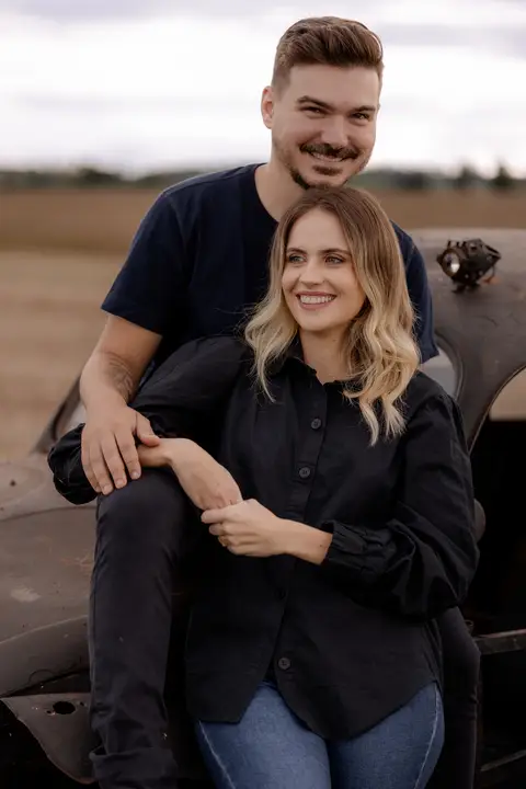 Noiva linda sorrindo com look all black para ensaio no campo com fusca'