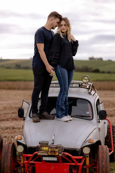 Casal em cima do capo do carro em ensaio no campo '