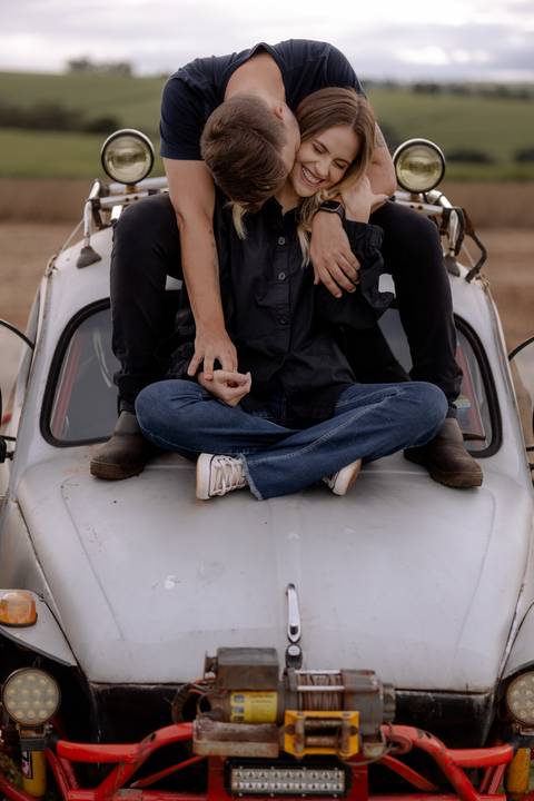 Foto criativa para casal em ensaio pré wedding com carro personalizado fusca antigo com rodas para trilha'