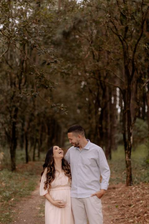 casal feliz com roupas lindas e leves para um ensaio de gestante na floresta '