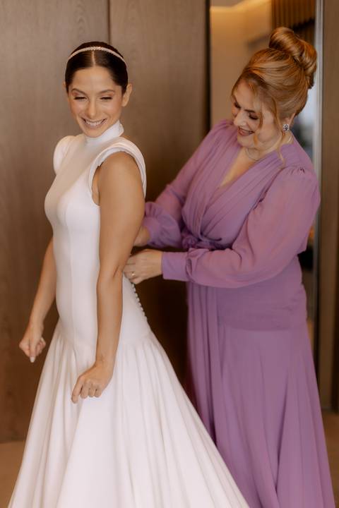mãe da noiva ajustando vestido de sua filha '
