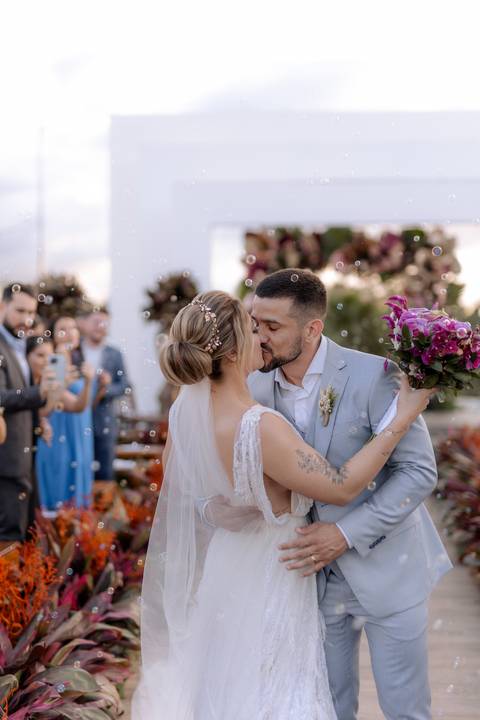 saída dos noivos em casamento ao ar livre com por do sol com bolinhas de sabão'