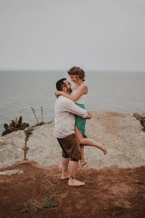 noiva feliz em colo de seu noivo para ensaio de casal'