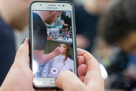 Foto da tela de um celular que mostra uma jovem de 15 anos sendo maquiada,clique de by Eli Matos'