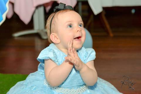 Alice bate palmas alegremente, com vestido azul, no clique de by Eli Matos'