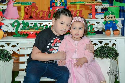 Ramona e Victor sentados em um banco de madeira branco, no clique de by Eli Matos'