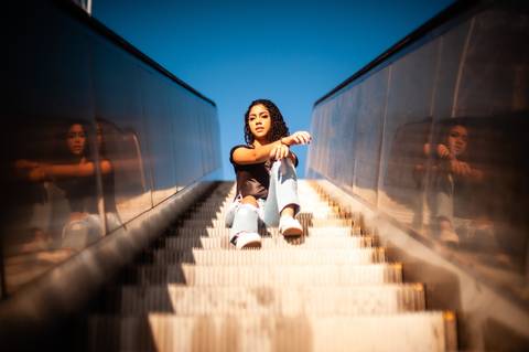 menina na  escada  rolante - sentada  - cabelo cacheado - calça  jeans clara  blusa preta  - ensaio fotografico de 15 anos  -  15 anos - 15 anos Fernanda '