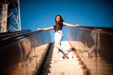 menina na  escada  rolante - sentada  - cabelo cacheado - calça  jeans clara  blusa preta  - ensaio fotografico de 15 anos  -  15 anos - 15 anos Fernanda '