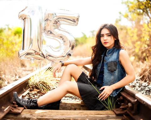 debutante na linha do tren sentada com saia preta  com 15 anos por tra z '