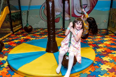Fotojornalismo de festa infantil: Giovanna brinca animadamente em um balanço na área kids do Plus Buffet em São Paulo'
