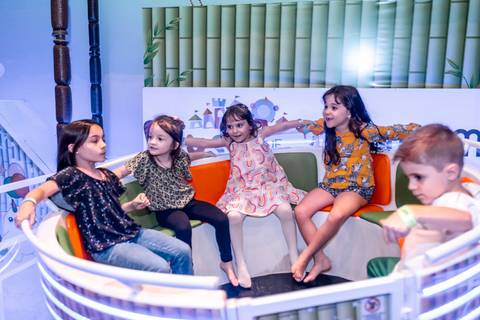 Fotografia espontânea em festa infantil: aniversariante Giovanna e amigas se divertindo em um dos brinquedos do Plus Buffet em São Paulo'