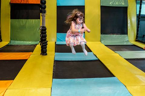 Fotografia de festa infantil no Plus Buffet: aniversariante Giovanna pula com alegria na cama elástica durante sua festa em São Paulo.'