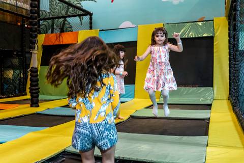 Fotografia espontânea de aniversário infantil: Giovanna e amigas pulando com muita energia na cama elástica do Plus Buffet, em São Paulo.'