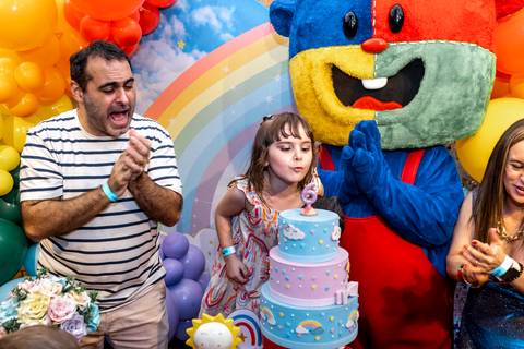 Fotógrafo de festa infantil em São Paulo captura o momento exato em que a aniversariante assopra a velinha de 6 anos no Plus Buffet, com os pais comemorando.'