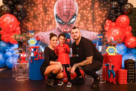 Fotografia de família em São Paulo: aniversariante Henry com os pais em frente à decoração do Homem-Aranha na festa no Kid Recanto Buffet.'