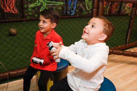 Fotógrafo de festa infantil em SP registra o aniversariante Henry e um amigo jogando videogame com empolgação no Kid Recanto Buffet.'