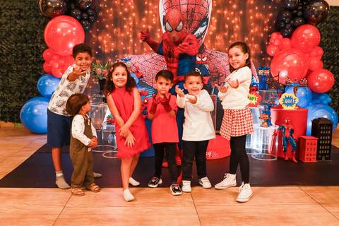 Fotografia de aniversário tema Homem-Aranha: Henry e seus amigos posam com o personagem vivo em frente à decoração no Kid Recanto Buffet em SP.