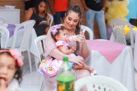 Registro espontâneo de mãe e filha em festa infantil em Guarulhos, um momento de carinho capturado por fotógrafo profissional.'