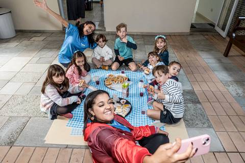 Foto de festa de aniversário infantil com as crianças fazendo um piquenique e tirando uma selfie com a recreadora no Tatuapé.'
