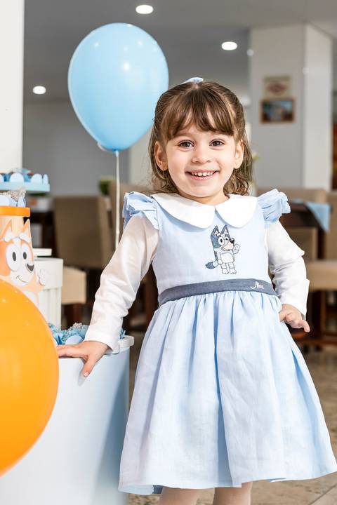 Foto de festa de aniversário infantil da Alice sorrindo ao lado da decoração Bluey em sua comemoração de 3 anos no Tatuapé.'