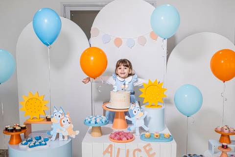 Foto de festa de aniversário infantil no Tatuapé, mostrando a aniversariante Alice na mesa do bolo com o tema Bluey.'