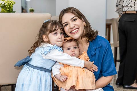 Foto de festa de aniversário infantil em Guarulhos e Tatuapé, Alice abraçando a irmã no colo da mãe durante sua festa de 3 anos com tema Bluey.'