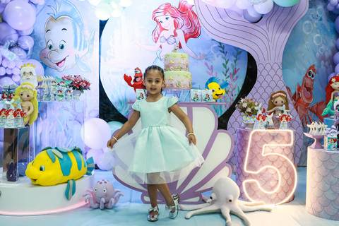Foto de aniversário infantil na Vila Maria, com a aniversariante Melissa posando em frente à decoração da Pequena Sereia no Buffet Magia Kids Prime.'