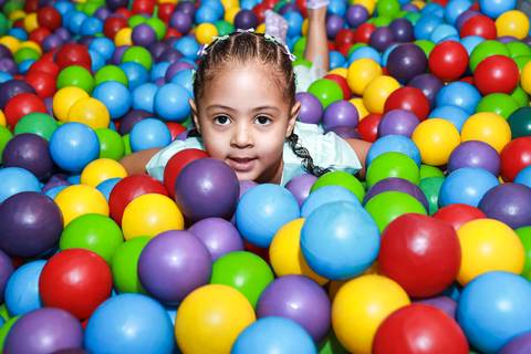 Fotografia de aniversário infantil na Vila Maria com um close da aniversariante Melissa sorrindo na piscina de bolinhas coloridas.'