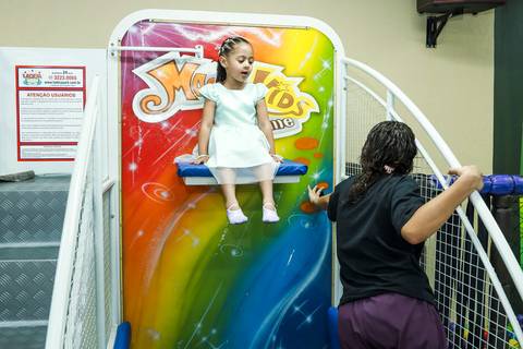 Foto de festa infantil na Vila Maria mostrando a alegria da aniversariante Melissa ao escorregar na piscina de bolinhas do Buffet Magia Kids Prime.'