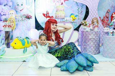Fotografia de aniversário infantil na Vila Maria, mostrando a aniversariante Melissa e a personagem Ariel fazendo poses divertidas em frente à decoração.'