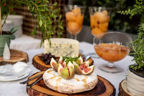 Chá de bebê. Detalhe da mesa de petiscos. Queijos, frutas e geléias, patês e pães. Álcool em gel para higienização'