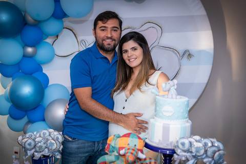 Chá de bebê. Casal em foto em frente à mesa de decoração'