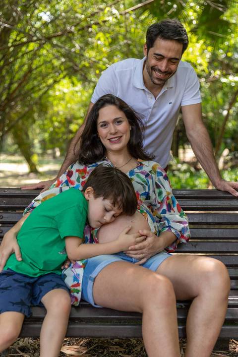 criança abraçando barrida da mãe gestante em banco no Jardim Botânico de São Paulo'