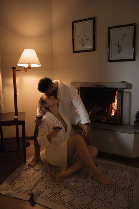 casal-de-roupão-em-frente-a-lareira-tomando-vinho'