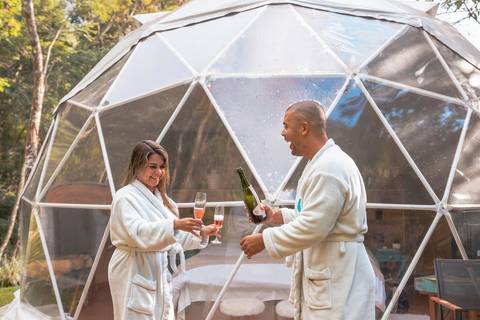 Casal na pousada BlueBear Cabins estourando espumante'