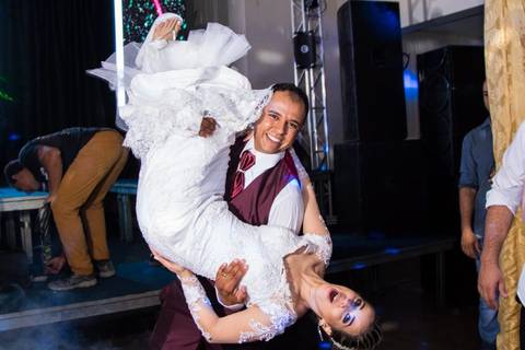 fotografia do  noivo virando a noiva de cabeça para baixo durante a festa de casamento '