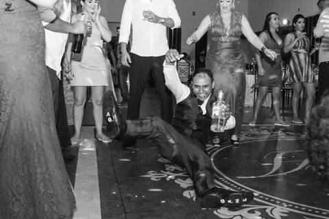 fotografia do noivo caindo com garrafa de tequila durante a festa de casamento'