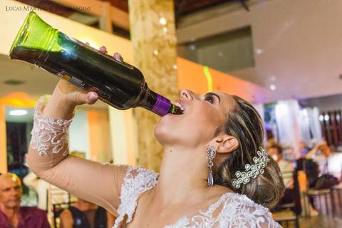 fotografia da noiva virando garrafa de catuaba na boca durante festa de casamento realizado em Araçuaí, Minas Gerais'