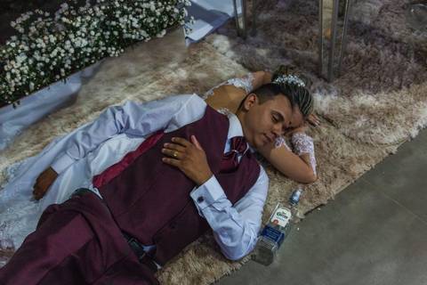 Fotografia dos noivos dormindo no tapete perto de uma garrafa de tequila em festa de casamento realizada em Araçuaí, Minas Gerais'